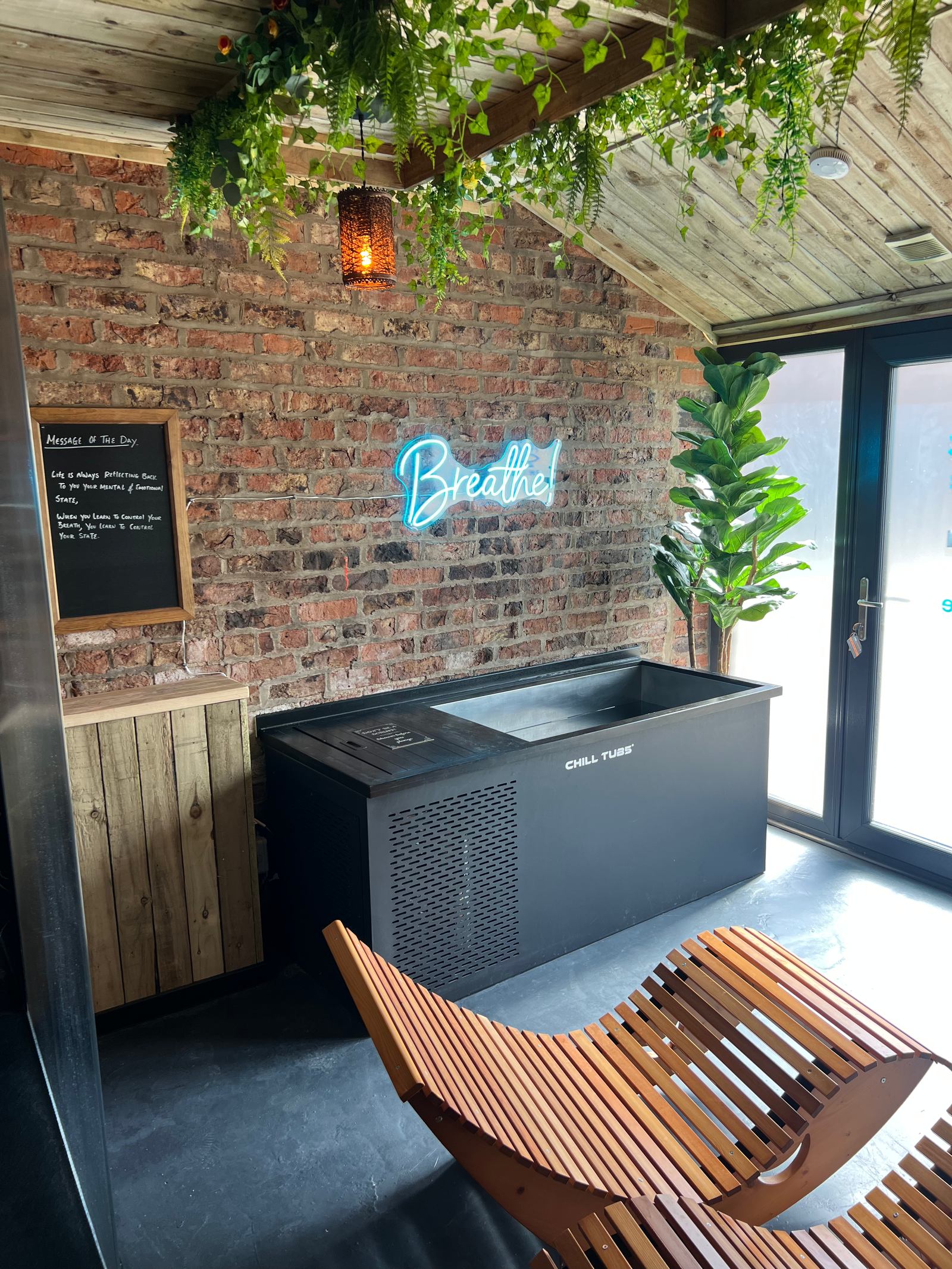 The Forge’s cold plunge and timber lounge seating beside the window.